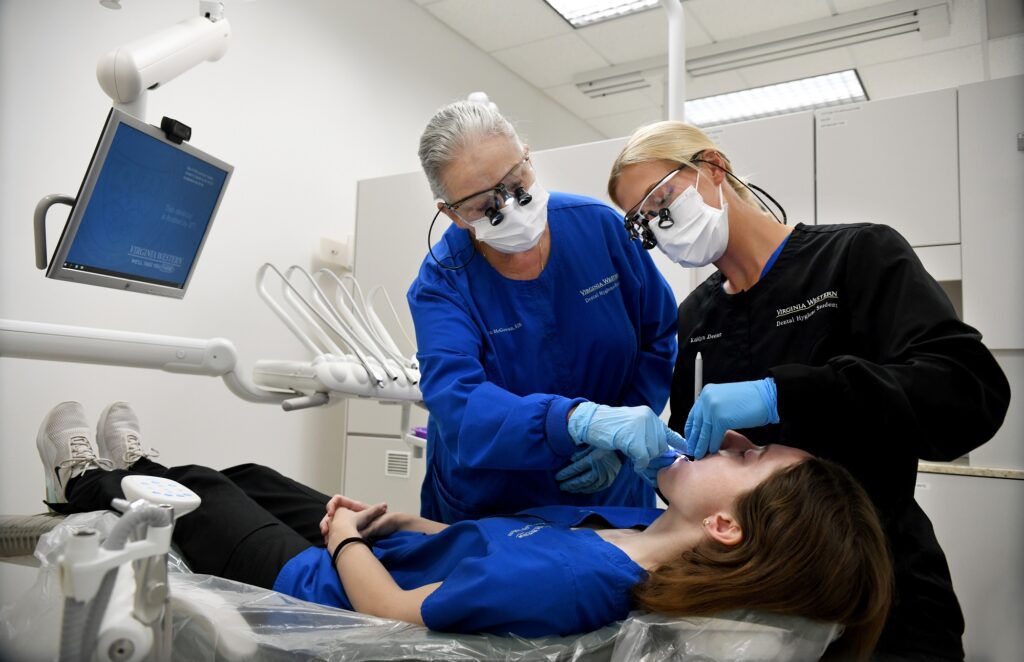 Clinic Coordinator Colleen McGowan (left) works with second-year Dental Hygiene students Elena Sable (patient) and Kaitlyn Deeter.